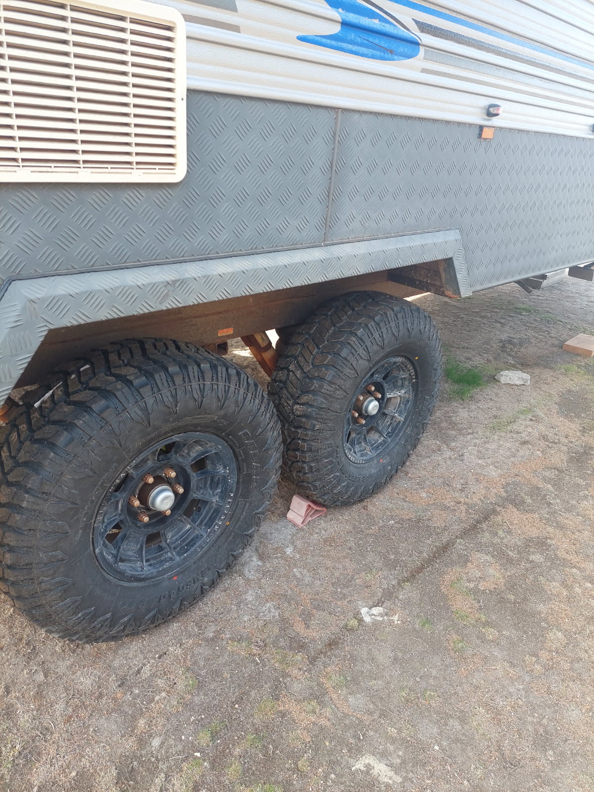 A caravan's tandem axle fitted with new mud terrain tyres on black alloy rims